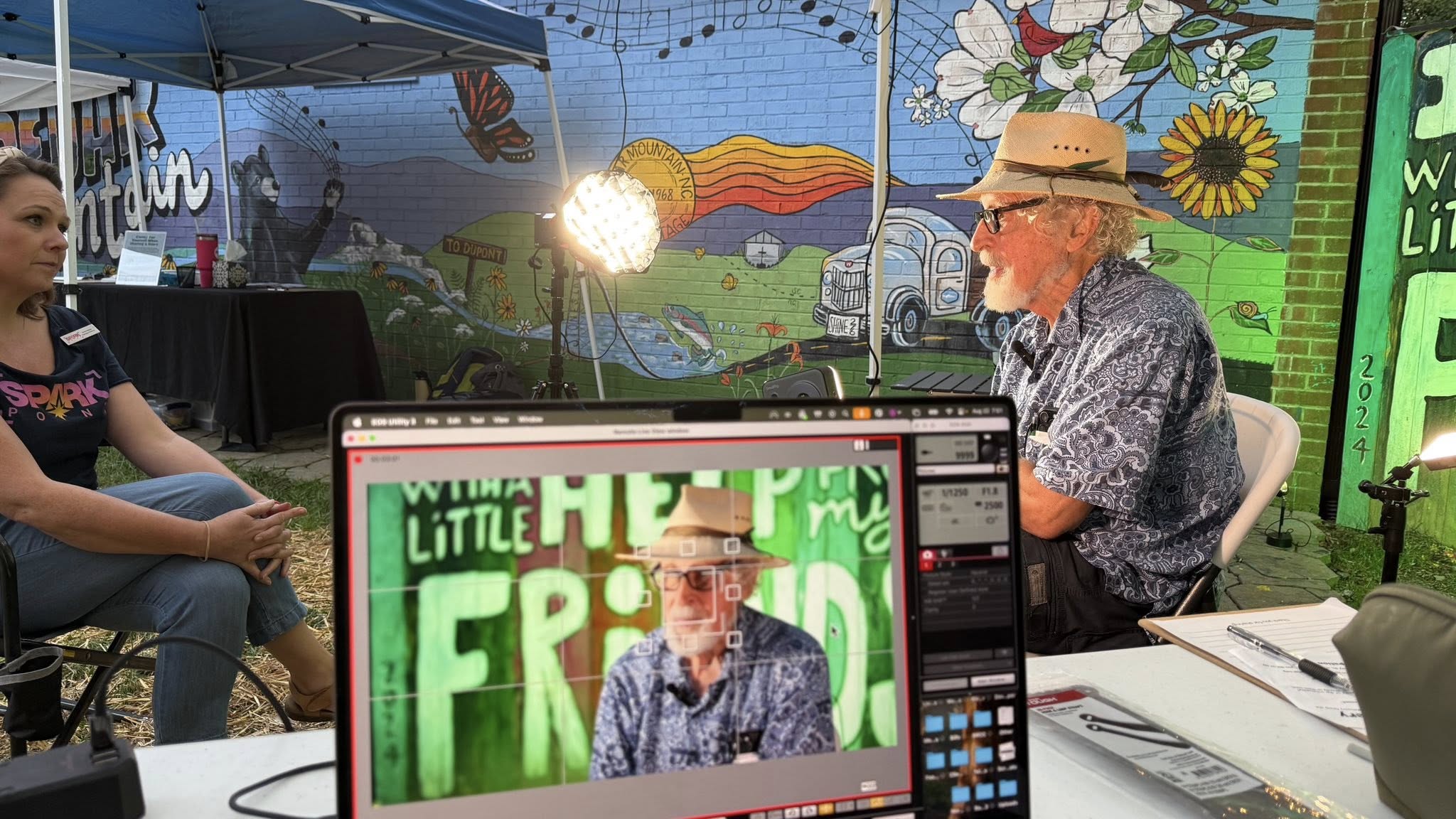 Interview taking place outdoors in front of a colorful mural