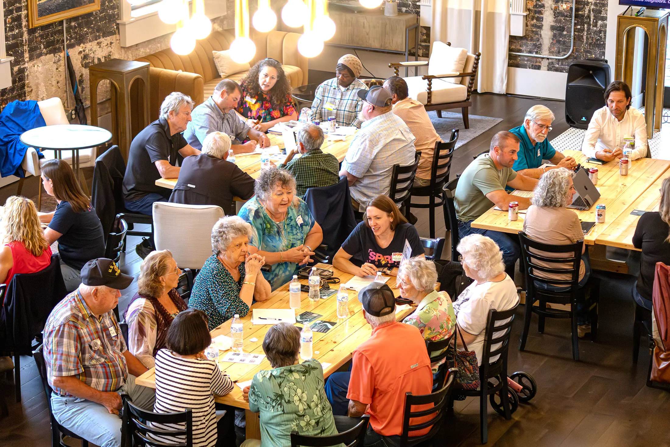 Community members gathered around tables for a facilitated Community Connectors conversation.